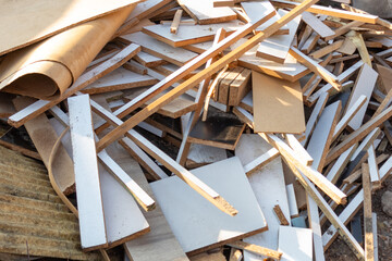 Pile of construction waste, including white and brown wooden debris, pieces of plywood, and old...