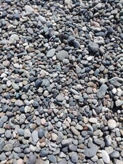 Big red stone and sea pebbles as frame on beach. Multicolor stone pebbles as natural abstract texture background with space for text. Close up colorful Pebble stone on coast. Filled full stone frame.