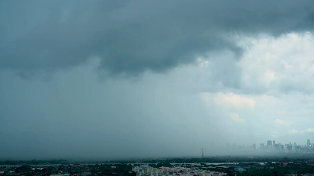 Dark clouds release tropical heavy downpour over cityscape, signaling sudden rainstorm.