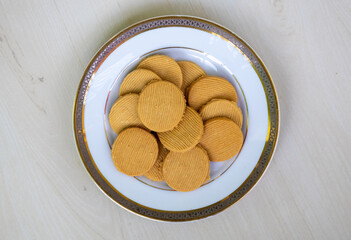Delicious sugar-free cookies on a white plate on a wooden background. Top view of tasty biscuits.