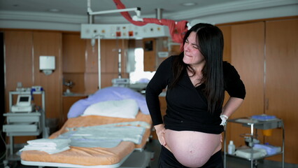 Woman experiencing contractions during pre labor standing at clinic before the birth of her baby...