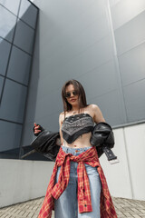 Cool fashionable urban stylish girl model with sunglasses in a fashion leather jacket with a...