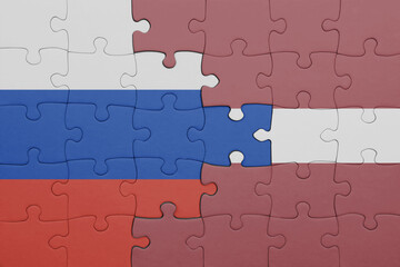 Fototapeta premium puzzle with the colourful national flag of latvia and flag of russia.