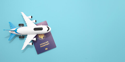 Layout of a white plane with a Ukrainian passport on a blue background. Summer vacation and plane travel, booking tickets