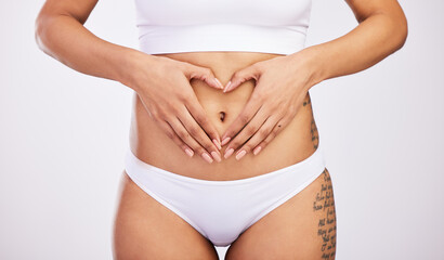 Woman, heart and hands on stomach in studio, diet and weight loss for gut health. Fitness, body wellbeing and abdomen of girl for wellness or digestion, balance and nutrition in white background
