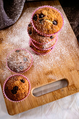 Tower of fresh banana/chocolate chip muffins dusted with powder sugar on vintage cutting board and tray