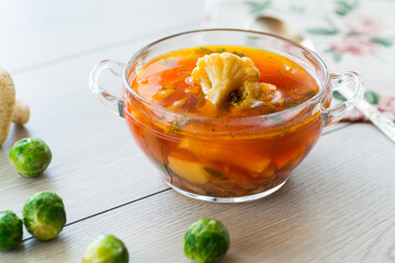 vegetable soup with Brussels sprouts and cauliflower, in a glass plate on a wooden table