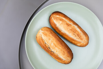 Burnt fresh wheat bread buns on a green plate and gray background