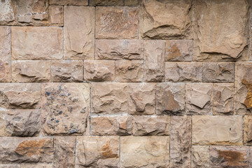 Solid house stone wall of roughly hewn stone closeup as stone background