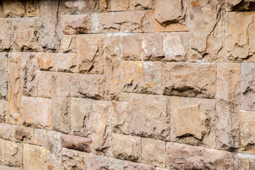 Solid house stone wall of roughly hewn stone closeup as stone background