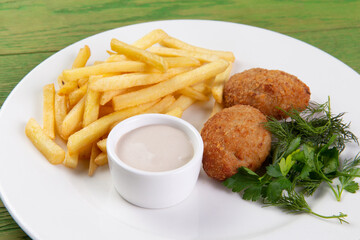 French fries and cutlets in a plate.