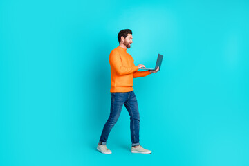 Photo of handsome nice man wear stylish clothes walk use device netbook isolated on aquamarine...