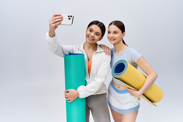 Two pretty, brunette teenage girls in sportive attire stand side by side in a studio.