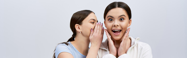 Two pretty, brunette teenage girls in sportive attire, making funny faces and gestures with their hands.
