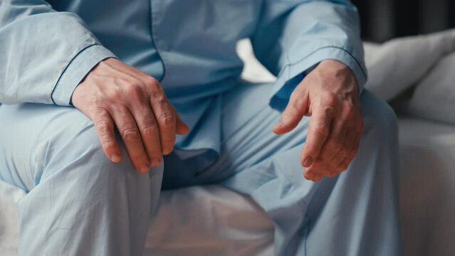 Close-up of a senior man sitting on the bed, distressed by mens health issues