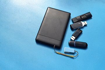 Several flash drives of different sizes on a blue background..