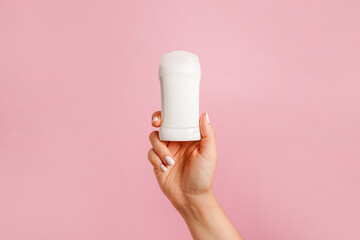 Hand holding white body deodorant on pink background