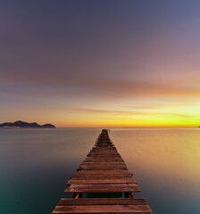 Obraz premium sunrise seascape with an old wooden dock leading out into the calm ocean waters