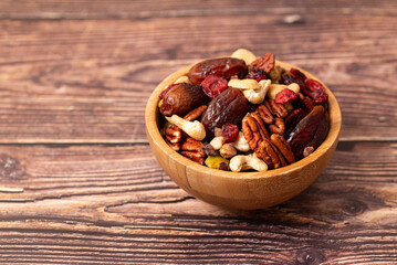 Natural raw foods ingredients and nuts arranged inside a bowl on a wooden table in a flat layout...