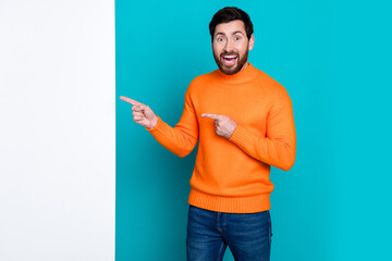 Photo of cheerful funny man wear stylish clothes presenting empty space isolated on cyan color...