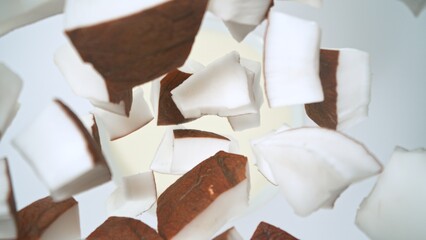 Fresh coconut pieces falling into cream, top down view
