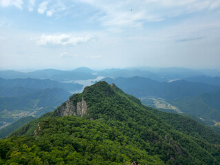 A mountain range with a lake in the valley below. The sky is clear and the mountains are covered in lush green trees