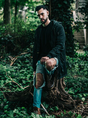 Pensive Young Man in a Forest at Dusk Wearing a Black Jacket

