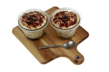 Tiramisu au café dans des ramequins avec une cuillère sur une planche à découper en gros plan sur fond blanc
