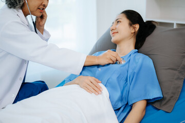 Obraz premium Doctor and young Female patient who lie on the bed while checking pulse, consult and explain with nurse taking note .
