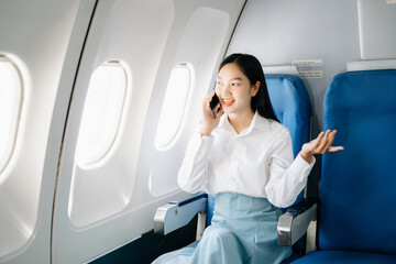 Asian executive excels in first class, multitasking with digital tablet, laptop. Travel in style,...