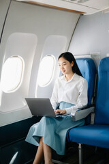 Asian executive excels in first class, multitasking with digital tablet, laptop. Travel in style,...