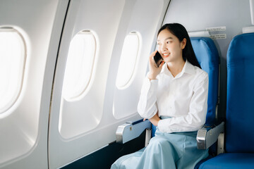 Asian executive excels in first class, multitasking with digital tablet, laptop. Travel in style,...