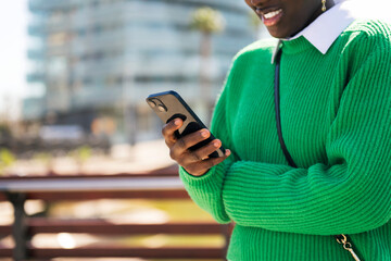 unrecognizable young african woman using mobile phone outdoors, concept of technology of...