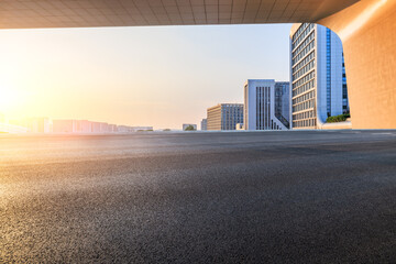 Fototapeta premium Asphalt road and modern city buildings at sunset