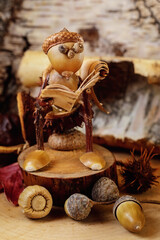 Autumn scene with a little gnome made of acorns reading a book on the closet. The picture is...