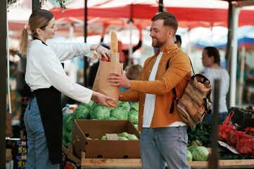Man is buying products on the street market or bazaar from woman