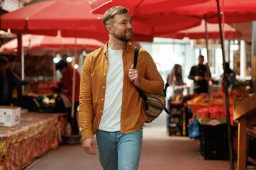 Going forward, looking at products. Handsome man is on the street market or bazaar