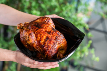 Woman showing a freshly roasted chicken, at home on the barbecue, ready to carve and eat, at a celebration,