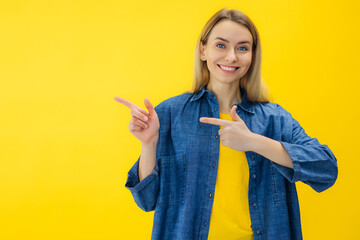 Smiling beautiful young woman look camera pointing fingers hands on copy space workspace isolated...