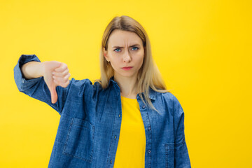 Young woman isolated on yellow background showing thumb down, disappointment concept.