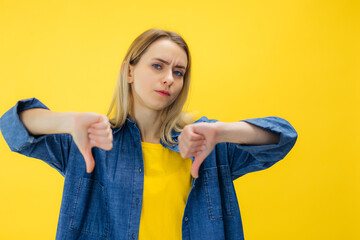 Discontent European woman shows diapproval sign, keeps thumbs down, expresses dislike, frowns face...