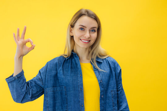 Smiling confident woman assure and guarantee all good, showing okay sign, have situation under control, like and praise promo offer, yellow background.