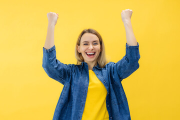 excited young lady standing isolated over yellow background make winner gesture.