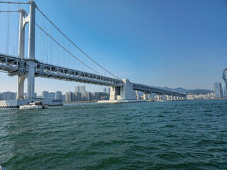 A large bridge spans a body of water, with a boat in the foreground. The bridge is a modern structure, and the water is calm and clear. Concept of tranquility and peacefulness, as the bridge