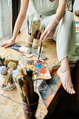 A woman in stylish attire sits gracefully on top of a wooden table.