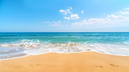 Fototapeta premium Golden sandy beach with gentle waves under a clear blue sky, creating a tranquil and idyllic seaside scene.