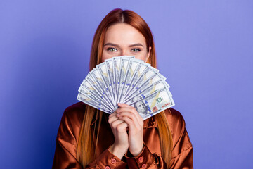 Photo of pretty young woman dollar bills cover face wear brown shirt isolated on violet color...