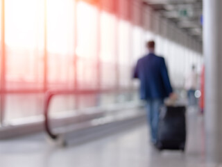 Fototapeta premium Unfocused photo of unrecognizable man walking with suitcase in airport terminal