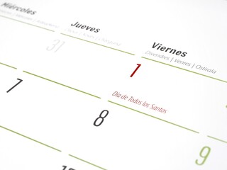 A group of unstuck blue push pins next to a monthly paper calendar for marking events or meetings