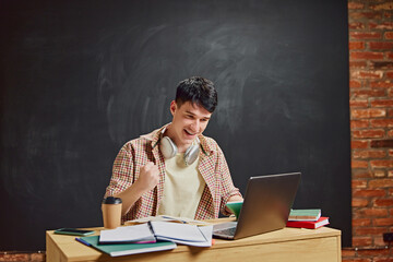 Happy smiling man, student celebrating successful study session, solving challenging task. Chalkboard background. Concept of education, studying, homework, youth, lifestyle